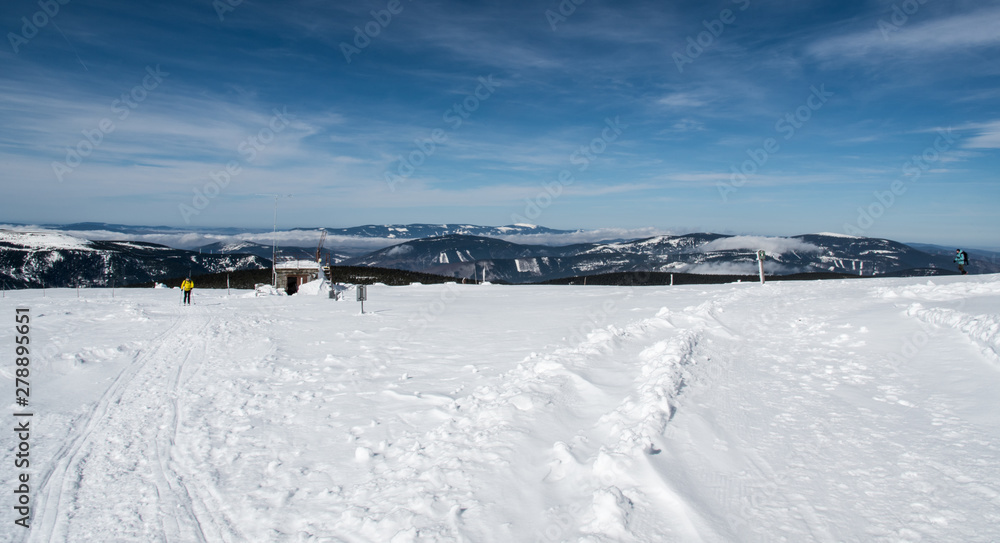 winter mountain panorama with many hills, few hikers and blue sky with clouds from Praded hill in Jeseniky mountains in Czech republic