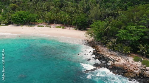 Aerial drone top view of beautiful exotic white sand beach and clear turquoise sea water in Thailand. Paradise beach. Green rainforest with coconut palm trees and volcanic stones.
