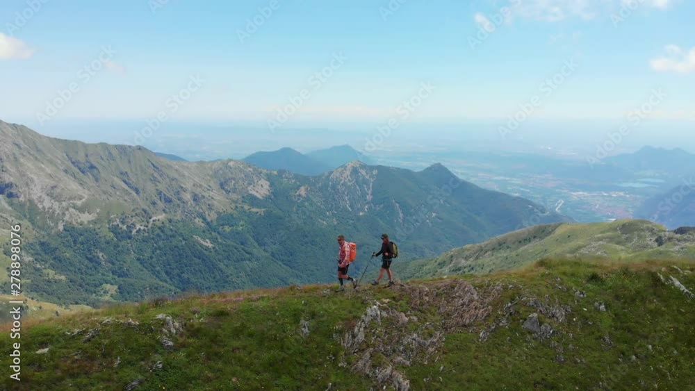 Aerial: couple backpackers hiking on mountain top, scenic landscape. Summer adventures on the Alps. Conquering success mature adult having fun wellbeing fitness Aerial: couple backpackers hiking on mountain top, scenic landscape. Summer adventures on the Alps. Conquering success mature adult having fun wellbeing fitness