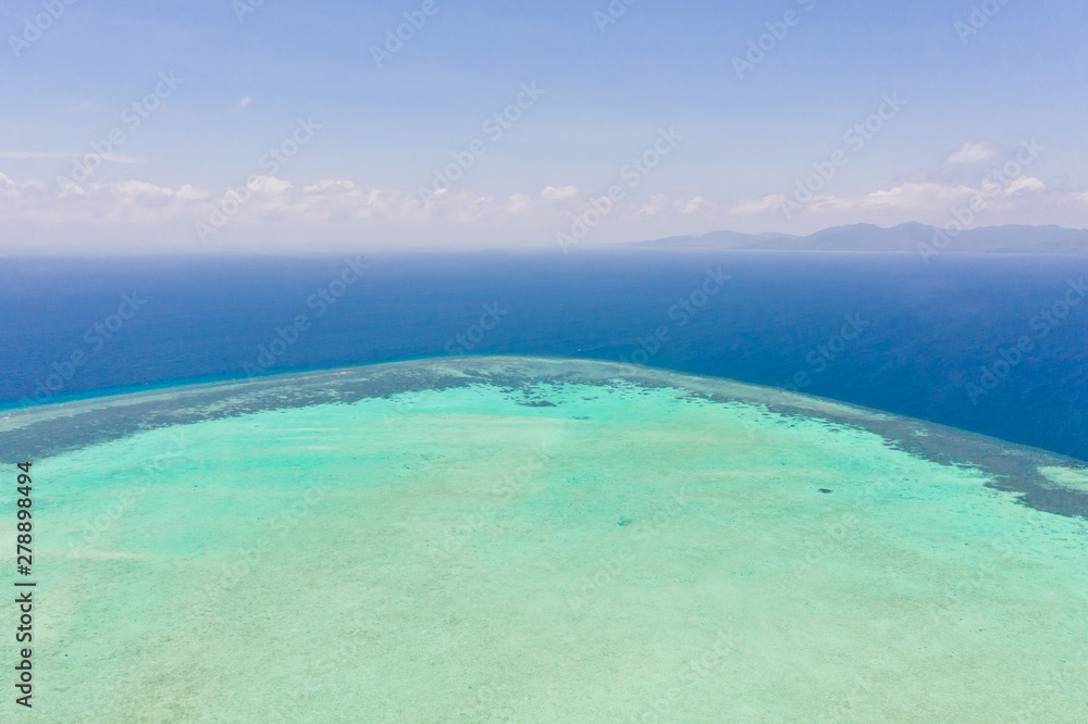 Obraz premium Atoll and blue sea, view from above. Seascape by day. Turquoise and blue sea water.