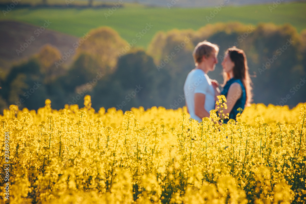 young couple in summer flower field with yellow flowers, rapeseed flower field in spring Germany young couple in summer flower field with yellow flowers, rapeseed flower field in spring Germany