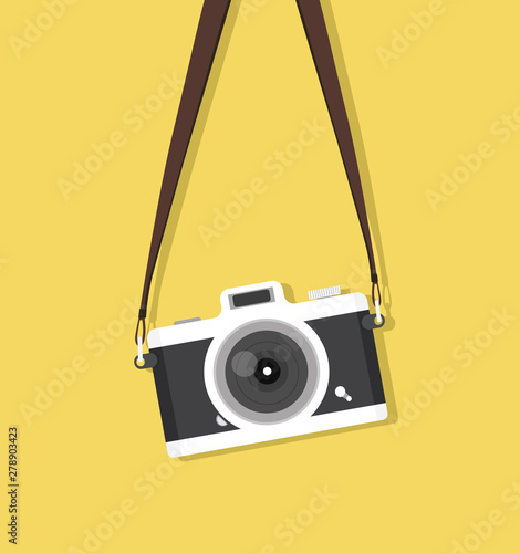 hanging vintage camera with strap on yellow background