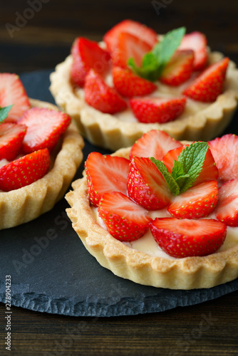 Canvas Print Tartlets with custard, strawberries and mint served on a slate plate