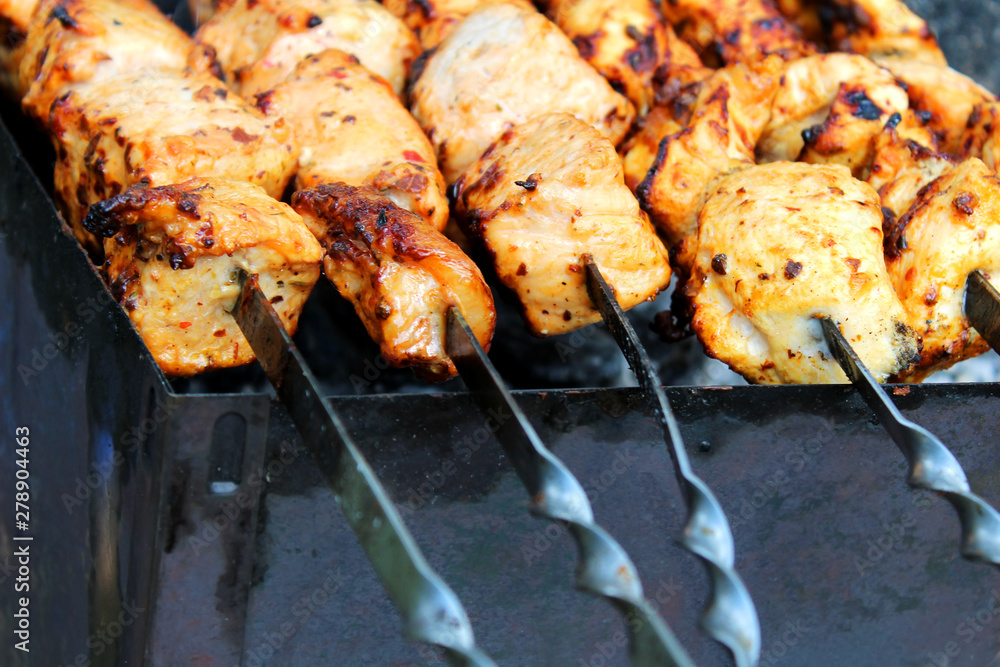 Pieces of meat on skewers cooking on the grill. Barbecue in the open air close-up