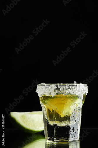 Tequila shot with lime and sea salt on black background