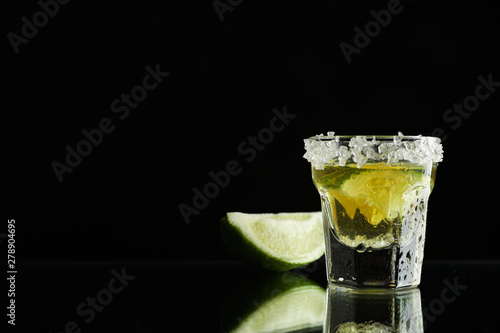Tequila shot with lime and sea salt on black background