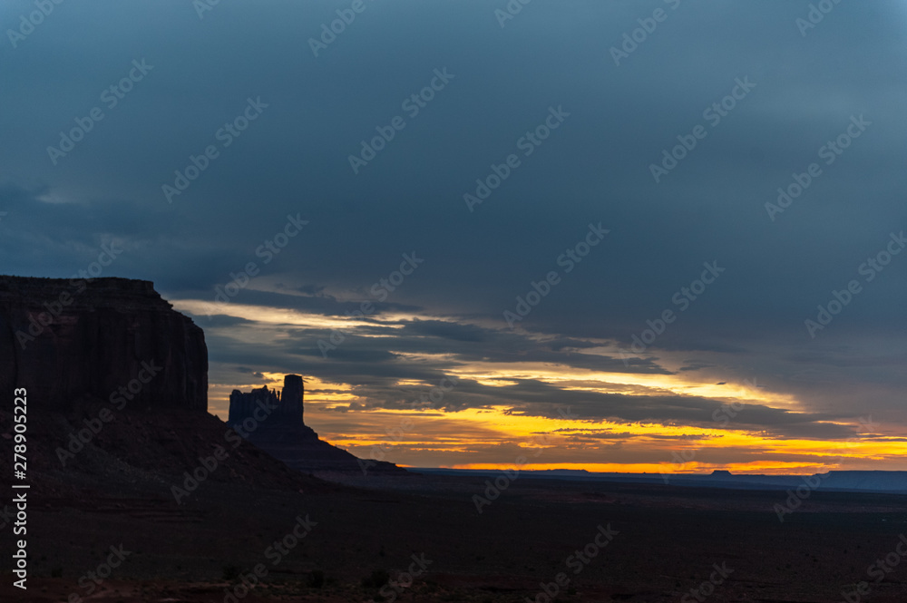 Early morning light of dawn, contasted against the black mesa walls of monument valley.