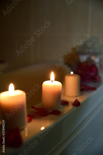 Three candles in bathroom with rose petals  home spa scene