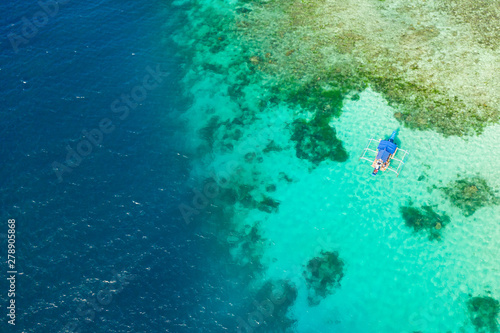 Boat on a coral reef. Sea surface with an atoll, coral reefs. Sea shoal and depth. Seascape with tourist boat.