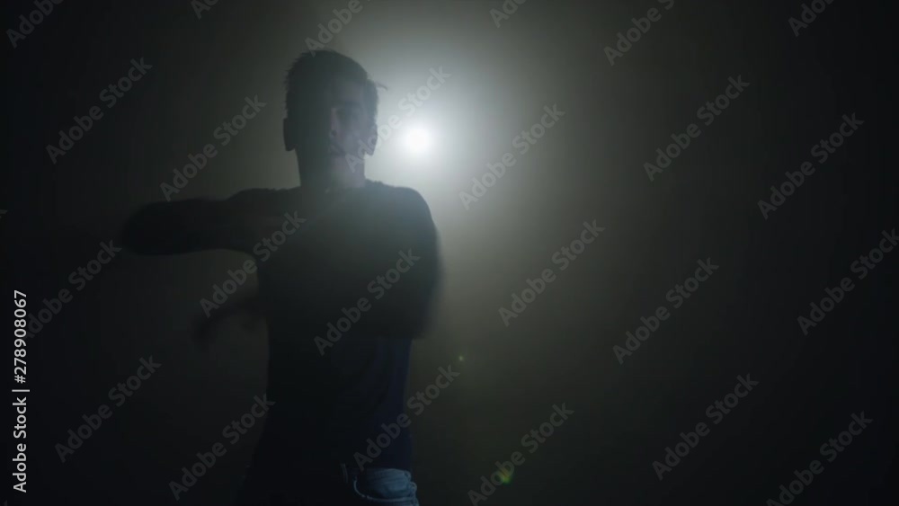 Silhouette of a talented young dancer dancing hip hop street dance on a stage in front of the spotlight Silhouette of a talented young dancer dancing hip hop street dance on a stage in front of the spotlight