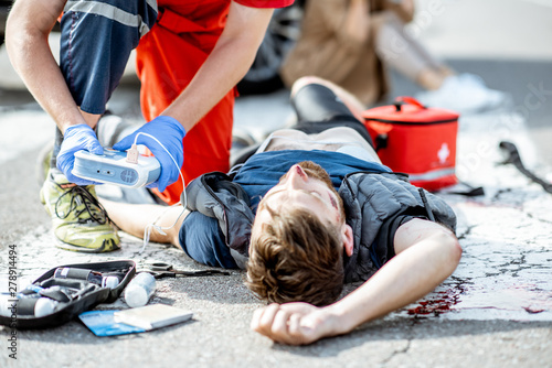 Canvas Print Ambluence worker applying emergency care with defibrillator to the injured bleed