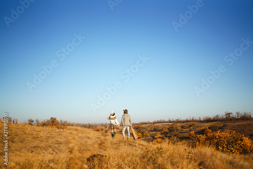 Lovely hipster couple enjoying each other. Couple wearing beautiful hats and sweaters. Lifestyle, happy couple of two play on a sunny day in the park. The concept of youth, love and lifestyle. 