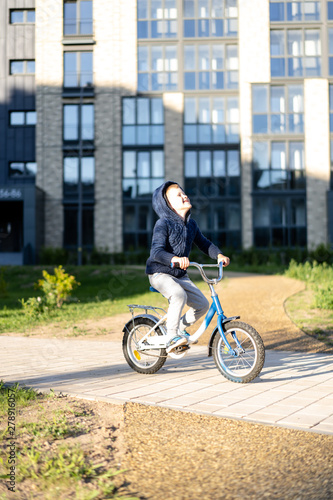 Fototapeta Naklejka Na Ścianę i Meble -  safety in a modern European city. A little happy boy rides a bicycle through a closed courtyard in a multi-storey urban building.
