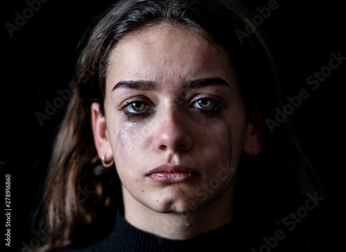 Fotografiet Sad young girl crying and suffering harassment online