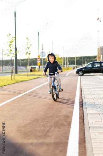 safety in a modern European city. little happy boy rides a bike on a secure rubberized bike path
