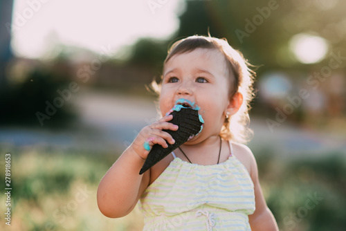cute girl eating ice cream in a black horn of blue color  funny and beautiful counter light