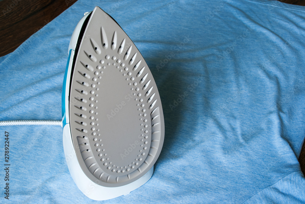 Electric iron and shirt on ironing board.