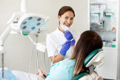 Woman dentist treats a patient. A woman in a mask sits in a dental chair in the clinic. Medicine  health  dentistry concept.