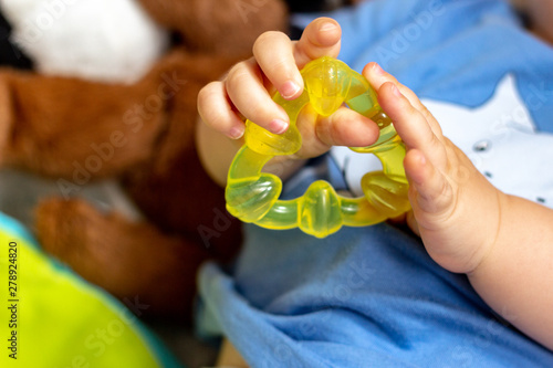 baby's hands holding a yellow biter