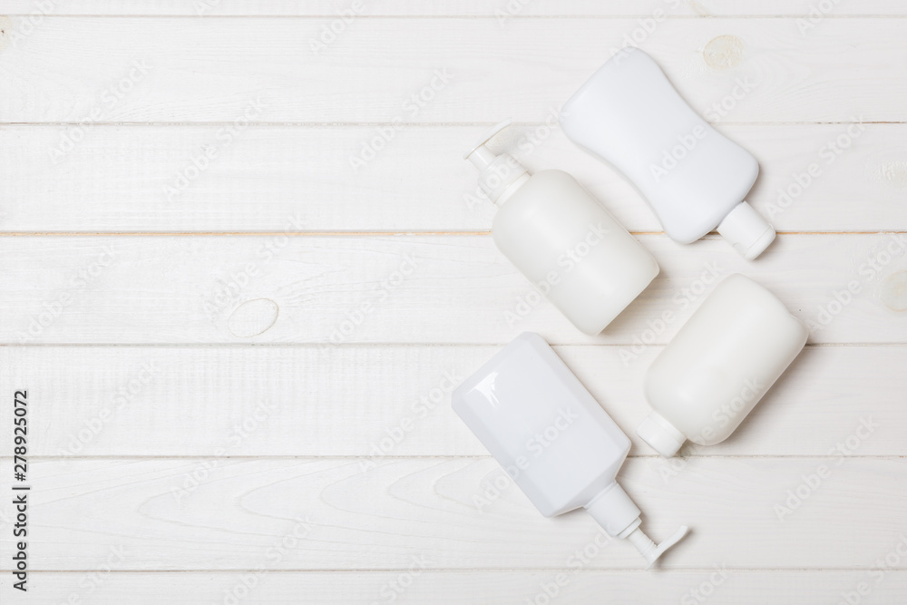 Obraz premium Set of White Cosmetic containers on wooden background, top view with copy space. Group of plastic bodycare bottle containers with empty space for you design