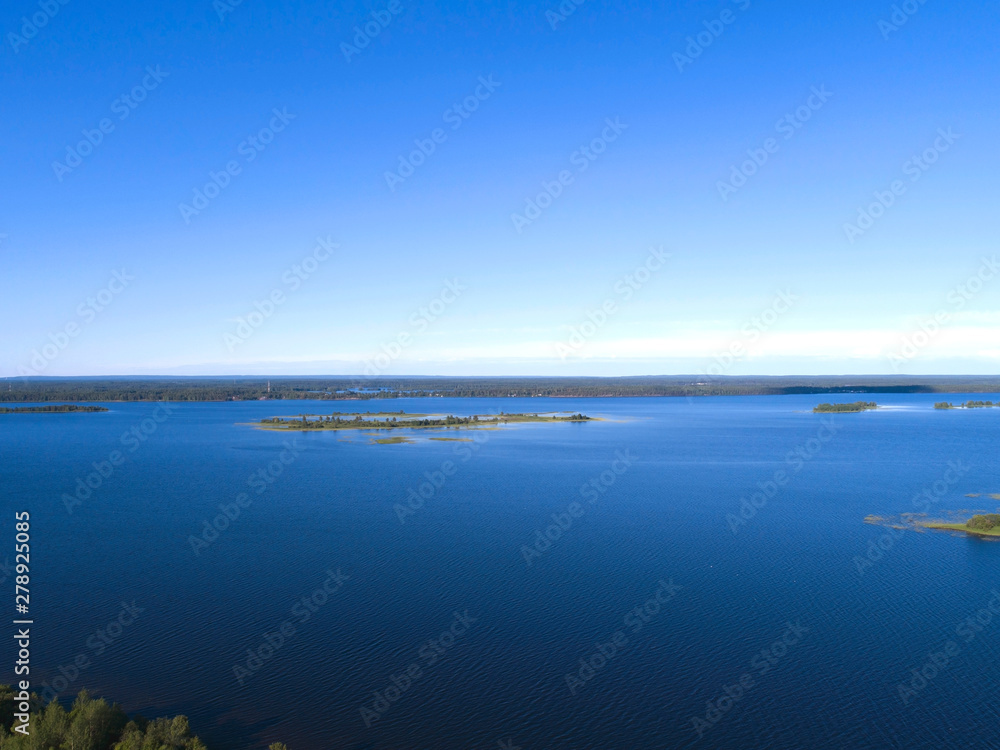 Aerial view on lake shore in summer day with green forest