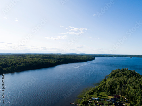 Aerial view on lake shore in summer day with green forest