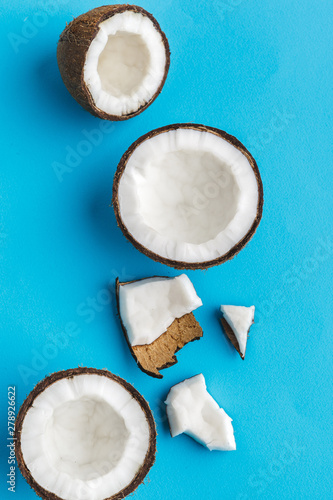 Slices of broken tropical coconuts on blue background. Top view