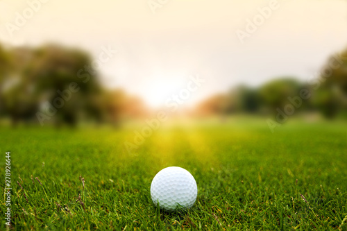 Golf ball on green grass on blurred beautiful landscape of golf course with sunrise,sunset time on background.	 photo