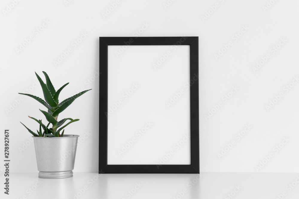 Black frame mockup with a aloe vera in a pot on a white table. Portrait orientation. Black frame mockup with a aloe vera in a pot on a white table. Portrait orientation.