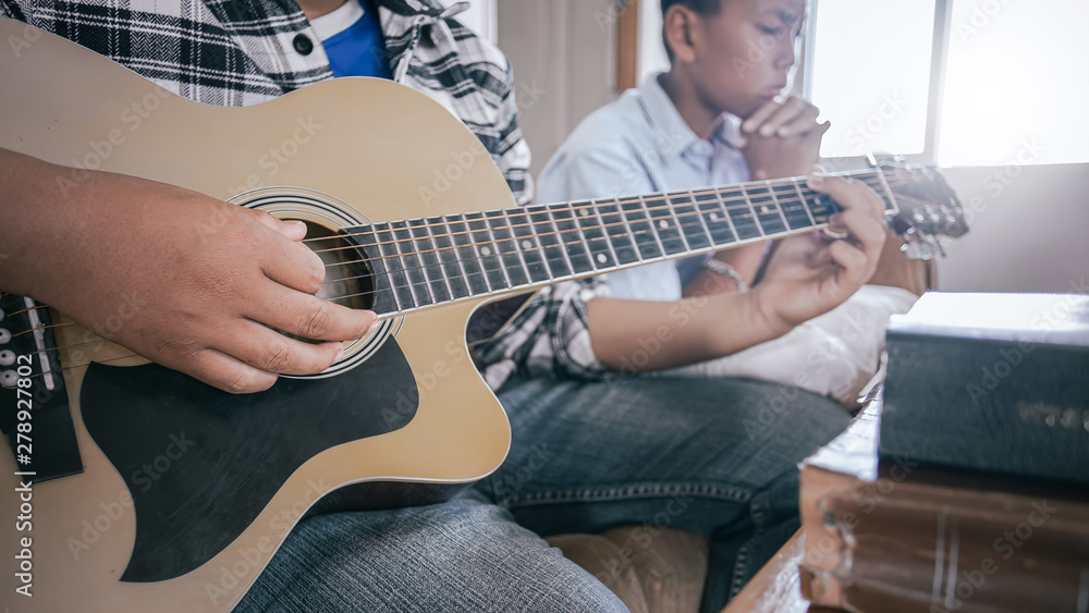 Fototapeta premium Young christian playing guitar and praying God on wooden table. christian concept.