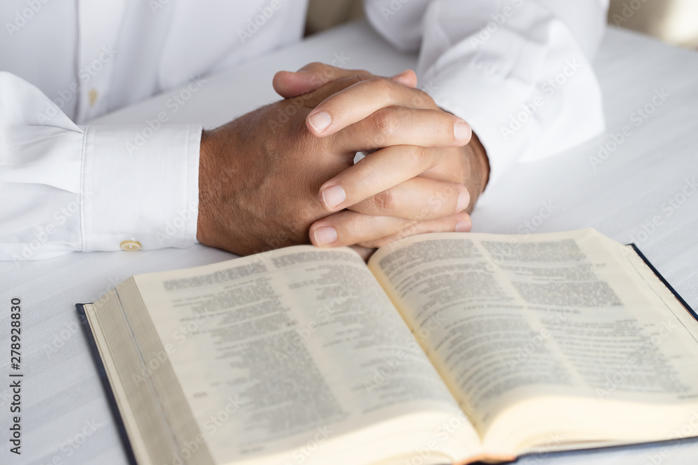 Fototapeta premium Close of hands in player on open Holy Bible. Man praying background.