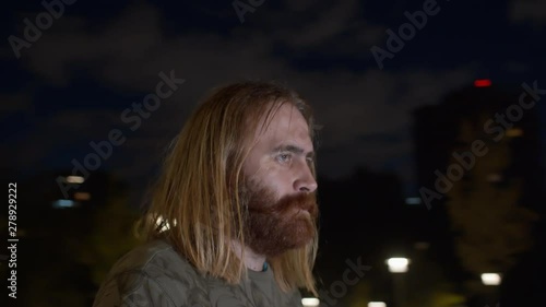 Point of view shot of brutal man while spinning on blurred background at night. He is serious at the biggining and smiling at the end of a clip photo