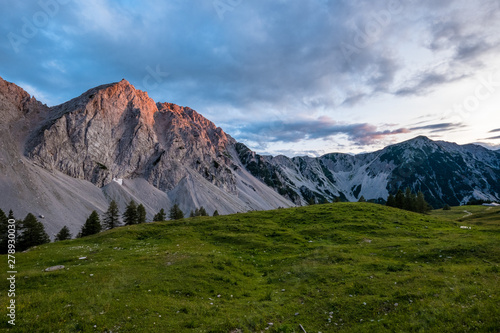 Sonnenuntergang auf einer idyllische Alm mit mächtigen Bergen im Hintergrund in den österreichischen Alpen