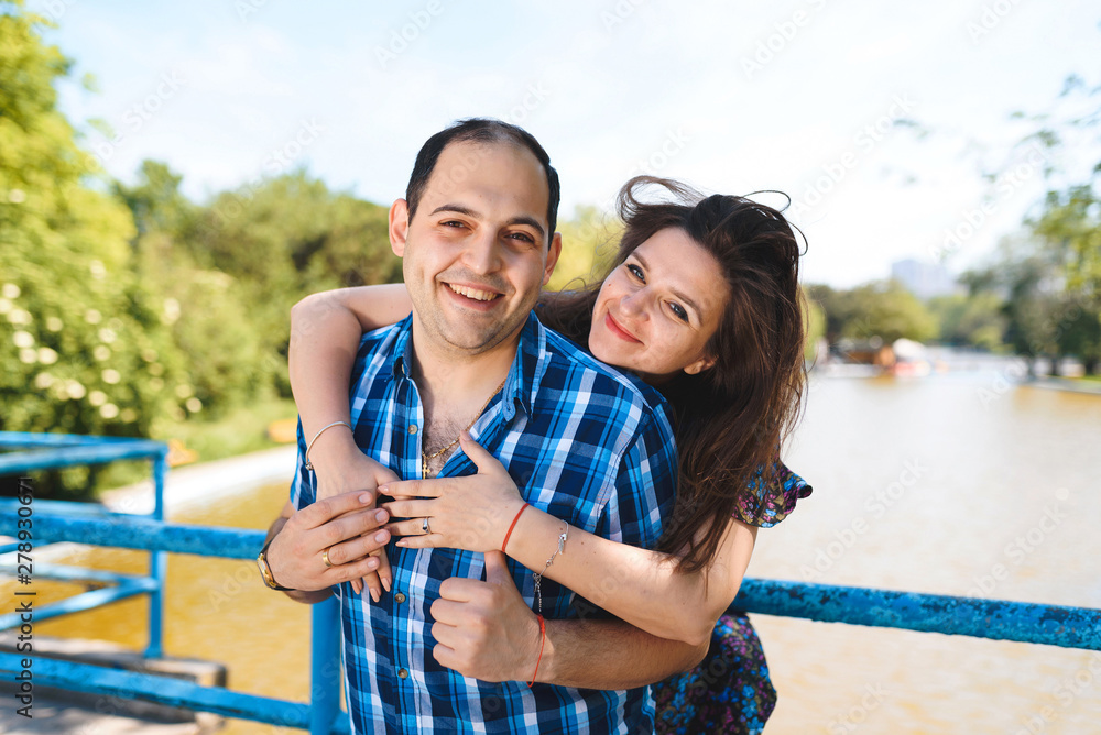 smiling woman hugging man on bridge over lake smiling woman hugging man on bridge over lake