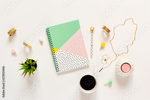 Flat lay desk table. Workspace with modern notebook, stationery, succlent, jewelery and a cup of coffee on white table. Top view.