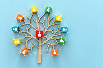 Business image of wooden tree with people icons over blue table, human resources and management concept