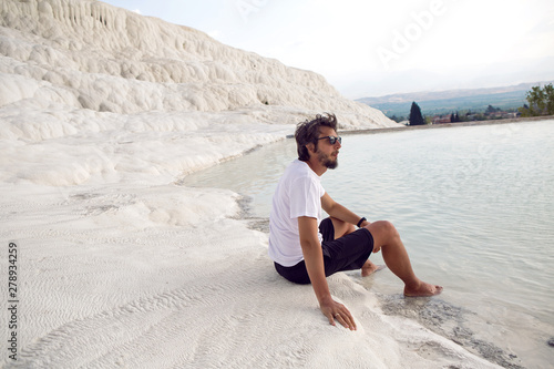 man with a beard in a white t-shirt and shorts sitting on a white mountain