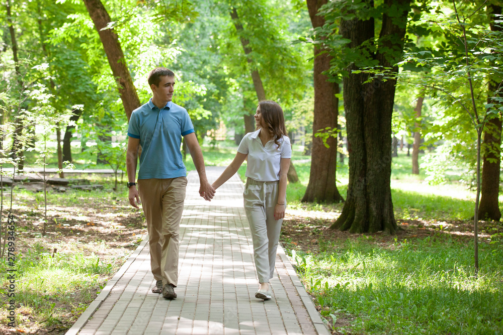 Couple walking hand in hand in a park - Romantic date outdoors Couple walking hand in hand in a park - Romantic date outdoors