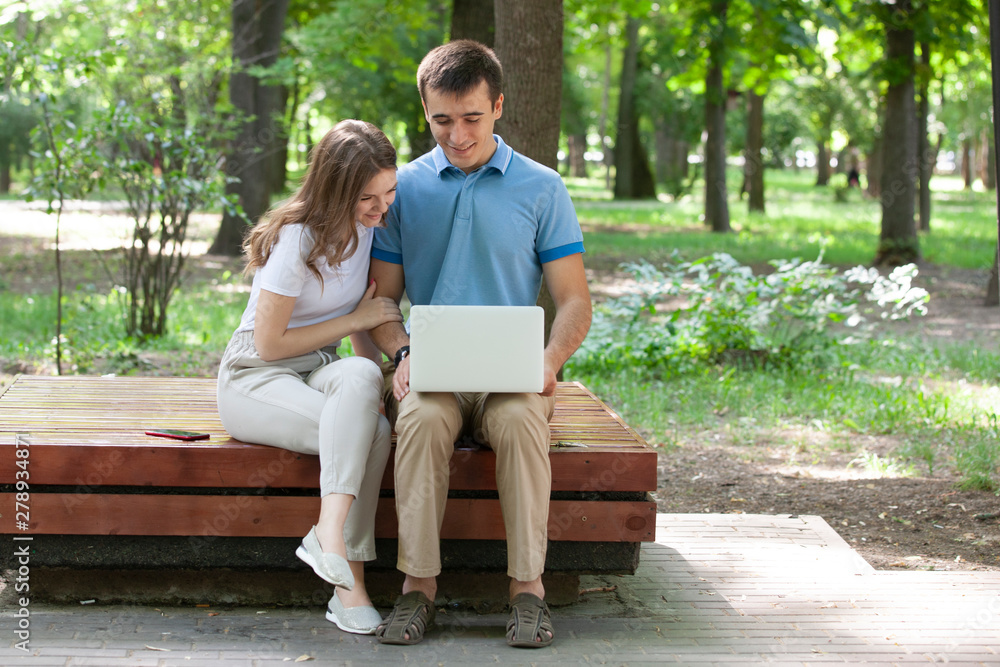 A guy and a girl are reading a book in a city park on a hot summer day. A guy and a girl are reading a book in a city park on a hot summer day.