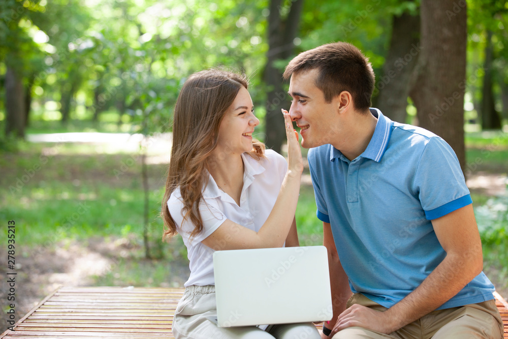 A guy and a girl are reading a book in a city park on a hot summer day.