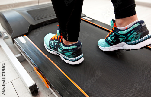 The woman's legs in new sneakers on the treadmill