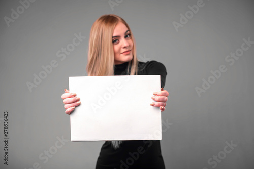 Blonde woman with blank paper on gray studio background