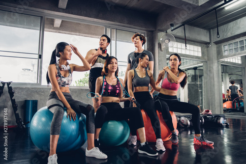 Group of young asian people in sportswear talking after a workout in gym