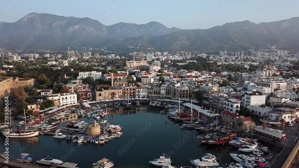 Aerial view of Kyrenia Harbour with ships in Kyrenia city (Girne), North Cyprus. Parking of pleasure boats, fishing boats and sailing yachts against the backdrop of the mountains and Kyrenia Castle Aerial view of Kyrenia Harbour with ships in Kyrenia city (Girne), North Cyprus. Parking of pleasure boats, fishing boats and sailing yachts against the backdrop of the mountains and Kyrenia Castle