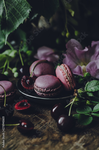 Macarons decorated with flowers on a dark rustic background