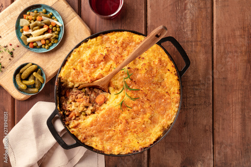 Shepherd's pie with pickles, herbs, and red wine, top shot on a dark rustic wooden background