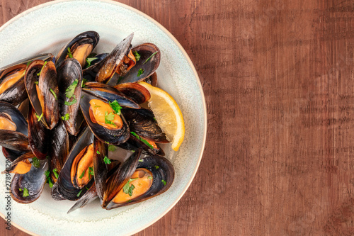 Marinara mussels, moules mariniere, close-up overhead shot on a dark rustic wooden background with copy space