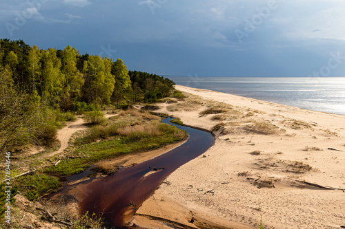 Fototapeta Naklejka Na Ścianę i Meble -  Seaside with a river flowing into the sea before thunderstorm in Saulkrasti in Latvia