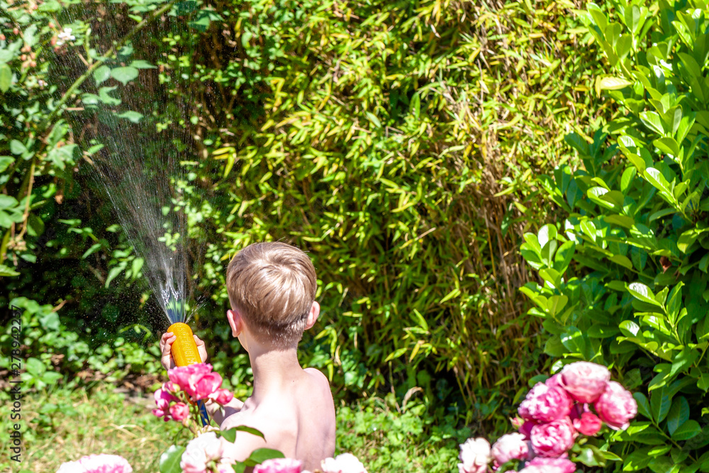 Happy little boy having fun with squirt gun in the garden Happy little boy having fun with squirt gun in the garden