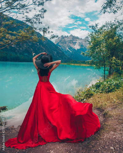 Woman in red dress on blue sky background of mountains